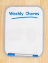 Weekly chores list on white dry erase board with marker on wood textured wall