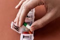 A weekly medicine dispenser opened for Wednesday, female hand taking pills and vitamins out of white pill box on