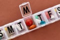 A weekly medicine dispenser opened for Wednesday, prescription pills and vitamins in a white pill box on terracotta