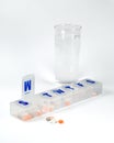 Weekly pill box with glass of water Royalty Free Stock Photo