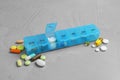 Weekly pill box with medicaments on grey table