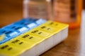 Pill holder on wood table with prescription bottles background