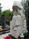 Weeping woman. Sculpture in the cemetery. The figure of a mother, wife or woman in a hood or stole. Lamentation for the