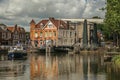 Boat passing by bascule bridge raised on tree-lined wide canal in cloudy day at Weesp.