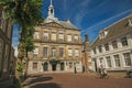 Elder man biking on street in front of the City Hall building on sunny day in Weesp.