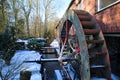 View on old water mill with blade wheel at rive with snow in winter