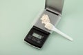 Weighing of guar gum powder on precise electronic digital scales. Food additive E412, exact dosage. Measuring spoon and sample