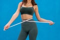 Weight loss concept, slim woman measuring her thin waist over blue background Royalty Free Stock Photo