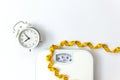 Weight loss control planning. White scale and measuring tape and timing alarm clock