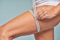 Weight loss. Cropped shot of a woman measuring her leg with a tape measure while standing against blue background Royalty Free Stock Photo