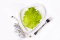 Weight loss diet. Fresh green leaf lettuce and measuring tape on heart shaped plate on white background. Healthy eating. Organic Royalty Free Stock Photo