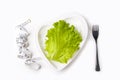 Weight loss diet. Fresh green leaf lettuce and measuring tape on heart shaped plate on white background. Healthy eating. Organic Royalty Free Stock Photo