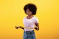 Weight loss and dieting concept. Sad african american woman measuring waist with tape, standing over yellow background Royalty Free Stock Photo