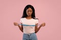 Weight loss and dieting. Upset African American woman measuring her breasts with tape on pink studio background