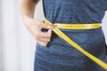 Weight loss and dieting. Young sporty woman measuring her belly with tape measure, closeup Royalty Free Stock Photo