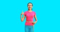 Weight loss and fitness concept - portrait of happy smiling slim young woman measuring her waist with yellow tape on blue Royalty Free Stock Photo