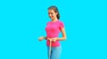 Weight loss and fitness concept - portrait of happy smiling slim young woman measuring her waist with yellow tape on blue Royalty Free Stock Photo