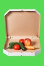 Weight loss and healthy eating or dieting concept. Open pizza box with raw vegetables in it isolated on green background.