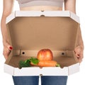 Weight loss and healthy eating or dieting concept. Slim girl with open pizza box and raw vegetables in it.