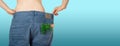 Weight loss and healthy eating or dieting concept. Slim girl in oversized jeans with a carrot, dill and parsley in the pocket.