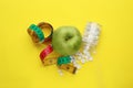 Weight loss pills, apple and measuring tape on yellow background, flat lay Royalty Free Stock Photo