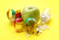 Weight loss pills, apple and measuring tape on yellow background Royalty Free Stock Photo