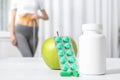 Weight loss pills with apple on table and woman measuring waist Royalty Free Stock Photo