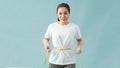 Weight loss, slim body, healthy lifestyle concept. Fit fitness girl measuring her waistline with measure tape on blue Royalty Free Stock Photo