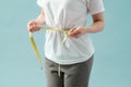 Weight loss, slim body, healthy lifestyle concept. Fit fitness girl measuring her waistline with measure tape on blue Royalty Free Stock Photo