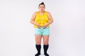 Weight loss, slimming, diet concept. Plus size, XXL woman in home clothing with measuring tape around the waist, showing Royalty Free Stock Photo