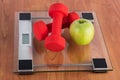 Weight scale with red dumbbell and fresh green apple on wooden floor Royalty Free Stock Photo