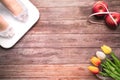 Weight scale white digital with women feet standing on scale and diet red apple bind with measuring tape on the wooden backgrounds