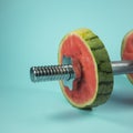 Weightlifting dumbbells made of steel bar and watermelon slices. On trendy pastel background Royalty Free Stock Photo