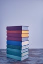 A weighty stack of bright smart books in textural fabric multi-colored covers on an old wooden table on a light background. Royalty Free Stock Photo