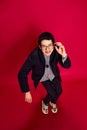 Portrait of stylish young man with glasses in strange pose over red background. Concept of student life, enjoying life Royalty Free Stock Photo