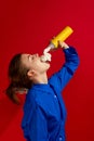 Weird people concept. Young girl tasting sweet whipped cream isolated over vintage red background. Concept of food