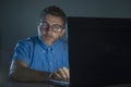 Weird tidy and neat nerd man in big glasses and shirt working happy using internet on laptop computer late night in the dark