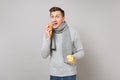 Weird young man in gray sweater, scarf holding lemons and licking oranges isolated on grey wall background. Healthy Royalty Free Stock Photo