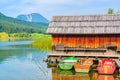 Three colourful fishing boats and wooden cabin on shore of Weissensee lake in summer landscape of Carinthia land, Austria Royalty Free Stock Photo