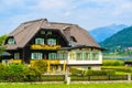 WEISSENSEE LAKE, AUSTRIA - JUL 6, 2015: Typical alpine guest house on green meadow in summer landscape of Weissensee lake, Austria