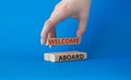 Welcome aboard symbol. Concept word Welcome aboard on wooden blocks. Beautiful blue background. Businessman hand. Business and Royalty Free Stock Photo