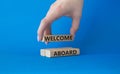 Welcome aboard symbol. Concept word Welcome aboard on wooden blocks. Beautiful blue background. Businessman hand. Business and Royalty Free Stock Photo