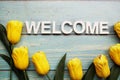 Welcome alphabet letters with yellow tulip flower on wooden background Royalty Free Stock Photo