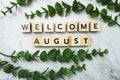 Welcome August alphabet letter with green leave flat lay on marble background