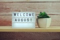 Welcome August word in light box on wooden shelves background