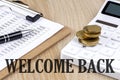 WELCOME BACK word written on wooden block on planner with coins, clipboard and a calculator Royalty Free Stock Photo