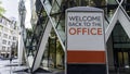 Welcome back to the office on a city-center sign in front of a modern office building