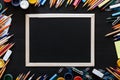 Welcome back to school background with kids supplies for modern primary education, color pencils, paints and frame on dark black