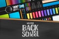 Welcome back to school sign on blackboard with wooden frame. Colorful stationery on dark background.