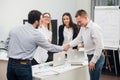 Welcome on board. Four business people sitting at the table while two of them shaking hands and smiling Royalty Free Stock Photo